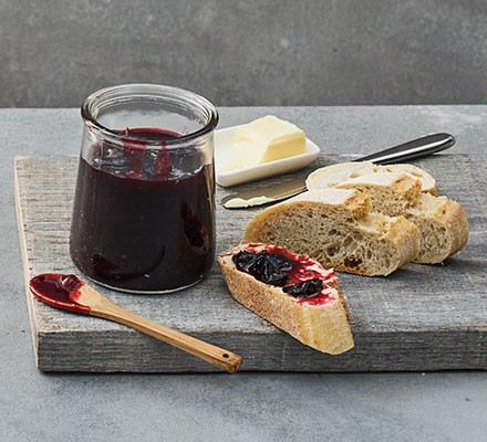Damson jam in a jar served with crusty bread and butter