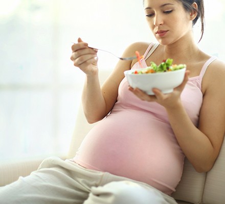 A pregnant woman enjoying a bowl of salad