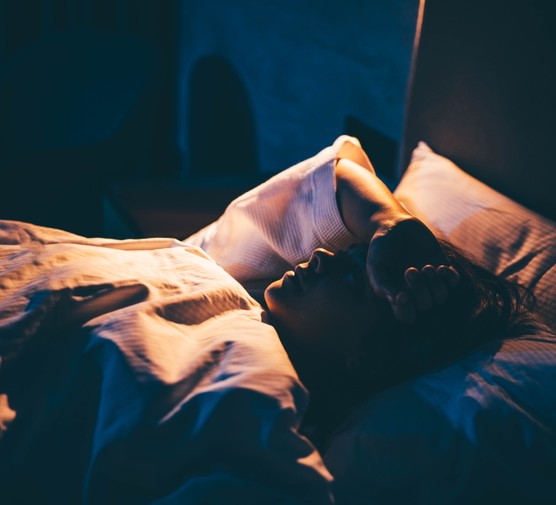 Woman lying in bed with hand on forehead