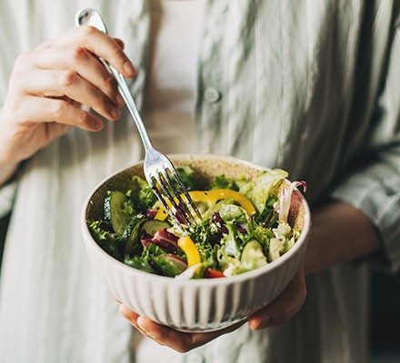 A woman eating salad from a bowl