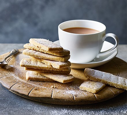 Shortbread biscuits served on a wooden board with a cup of tea