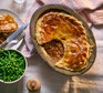 Slow cooker beef pie Beef pie with a serving removed next to a bowl of peas