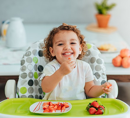 Child eating strawberry for breakfast