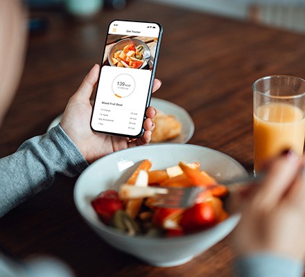 How much weight can you lose in a week? Someone using a mobile app to track their calories while eating a bowl of food
