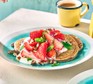 Vegan strawberry pancakes A serving of vegan strawberry pancakes on a plate with a cup of tea/coffee in the background